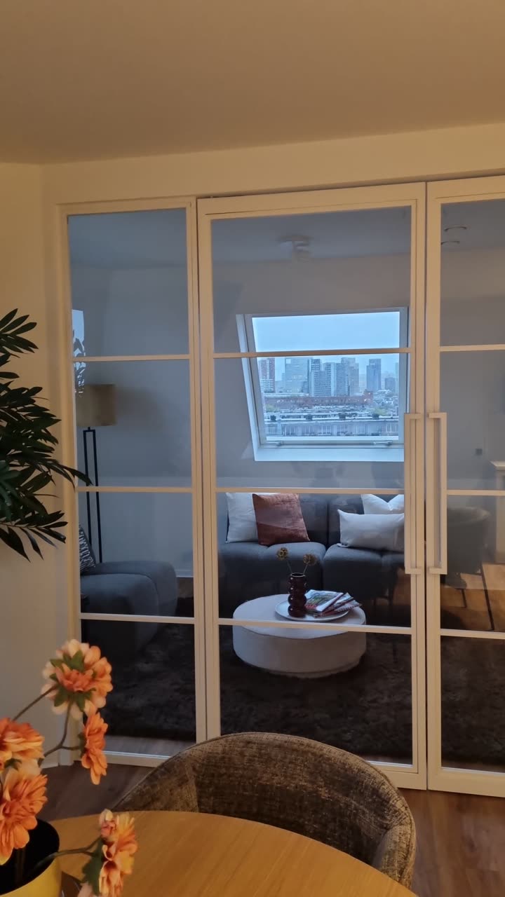Uitzicht op de skyline van Rotterdam vanuit woning 68-E, door het dakraam